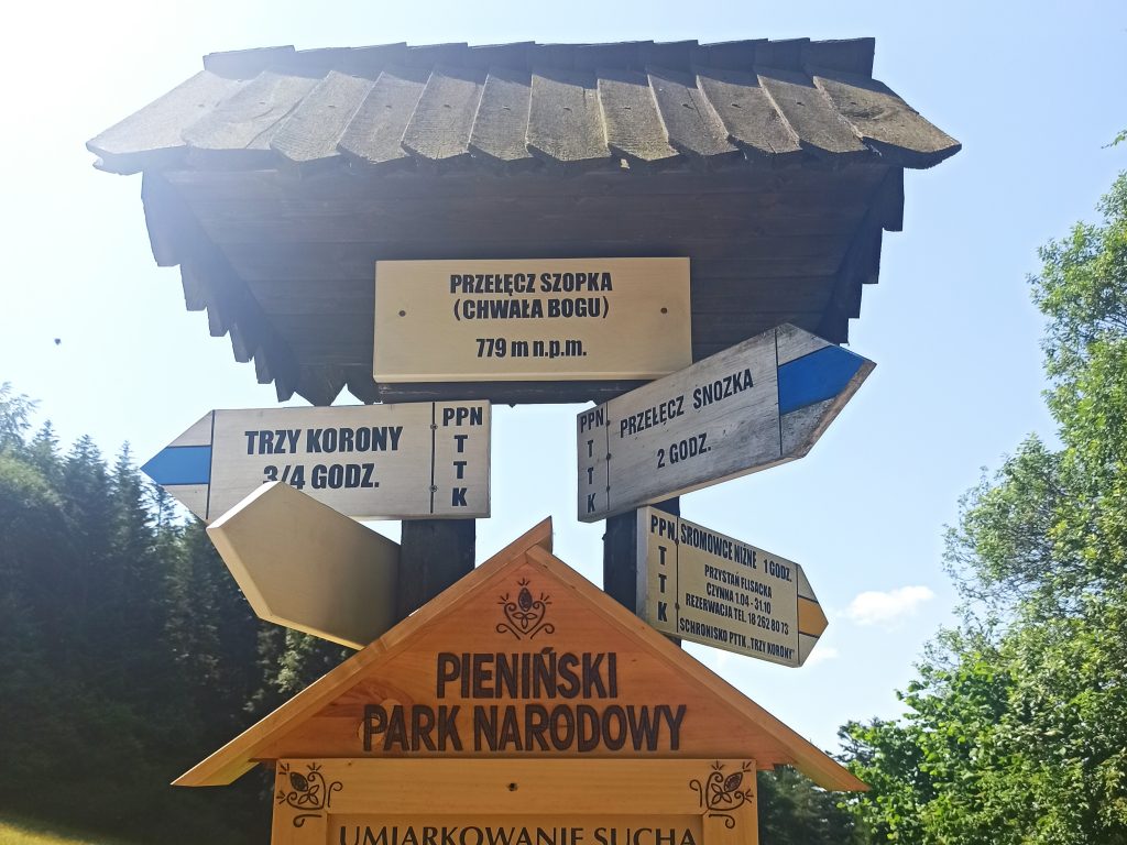 Tabliczka z nazwą Przełęczy Szopka i drogowskazy szlakowe.
